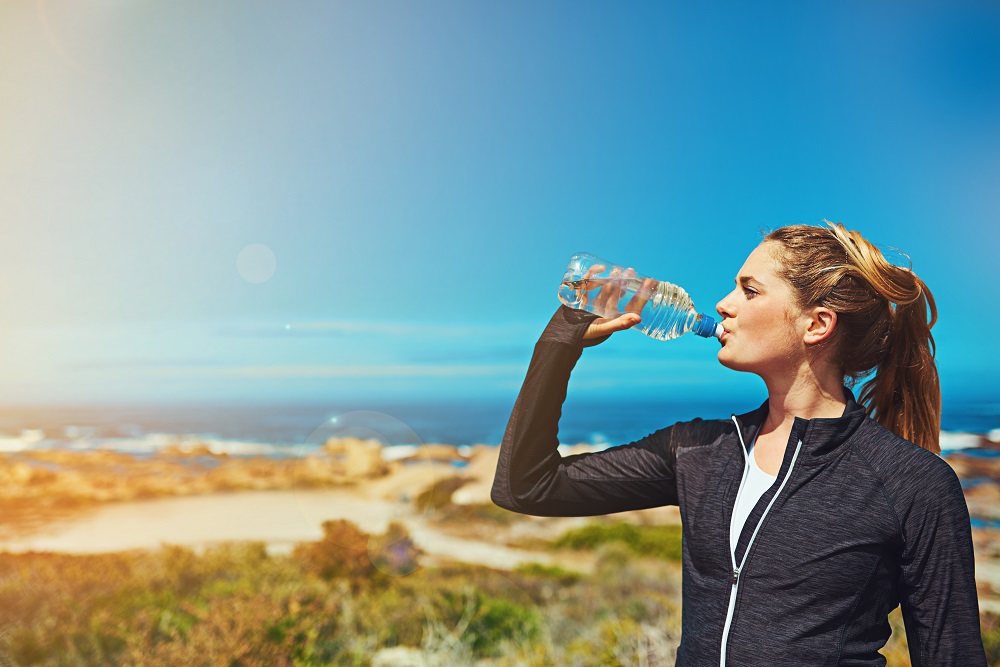 Frau trinkt Wasser nach dem Sport im Sommer