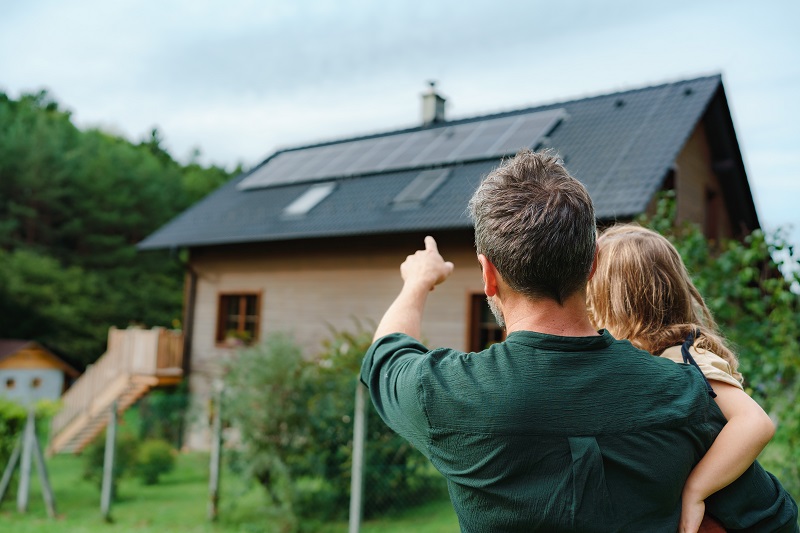 Vater mit Kind auf dem Arm, der auf ihr Haus zeigt