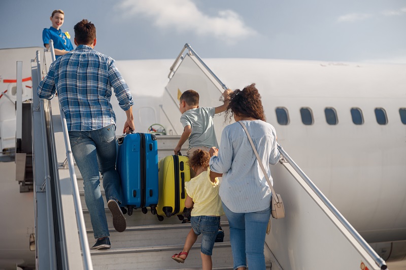 Familie, die die Treppe zum Flugzeug hochgehen um ins Flugzeug einzusteigen