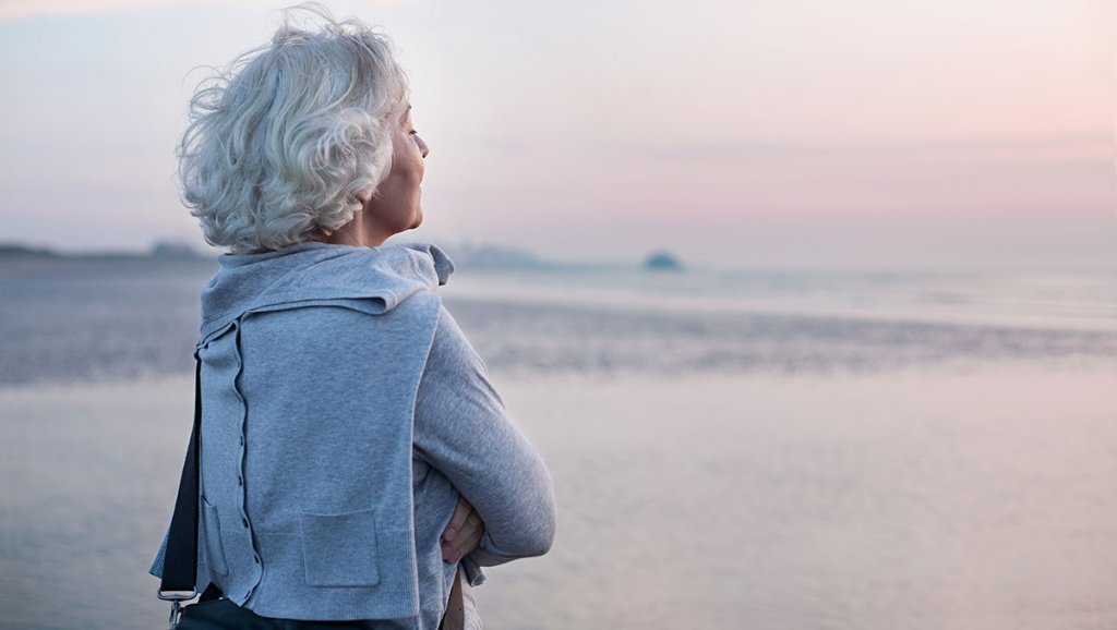 Ältere Frau, die am Meer steht