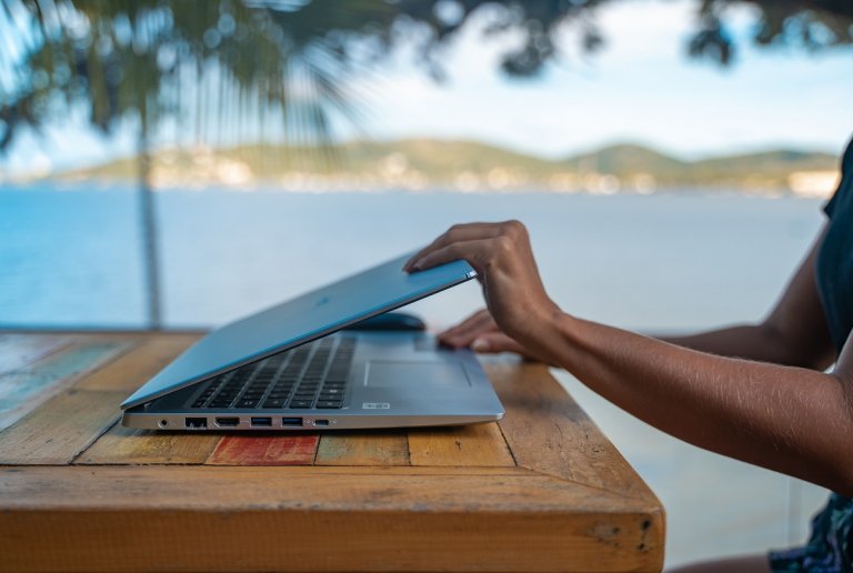 Eine Frau, die ihren Laptop am Meer aufklappt