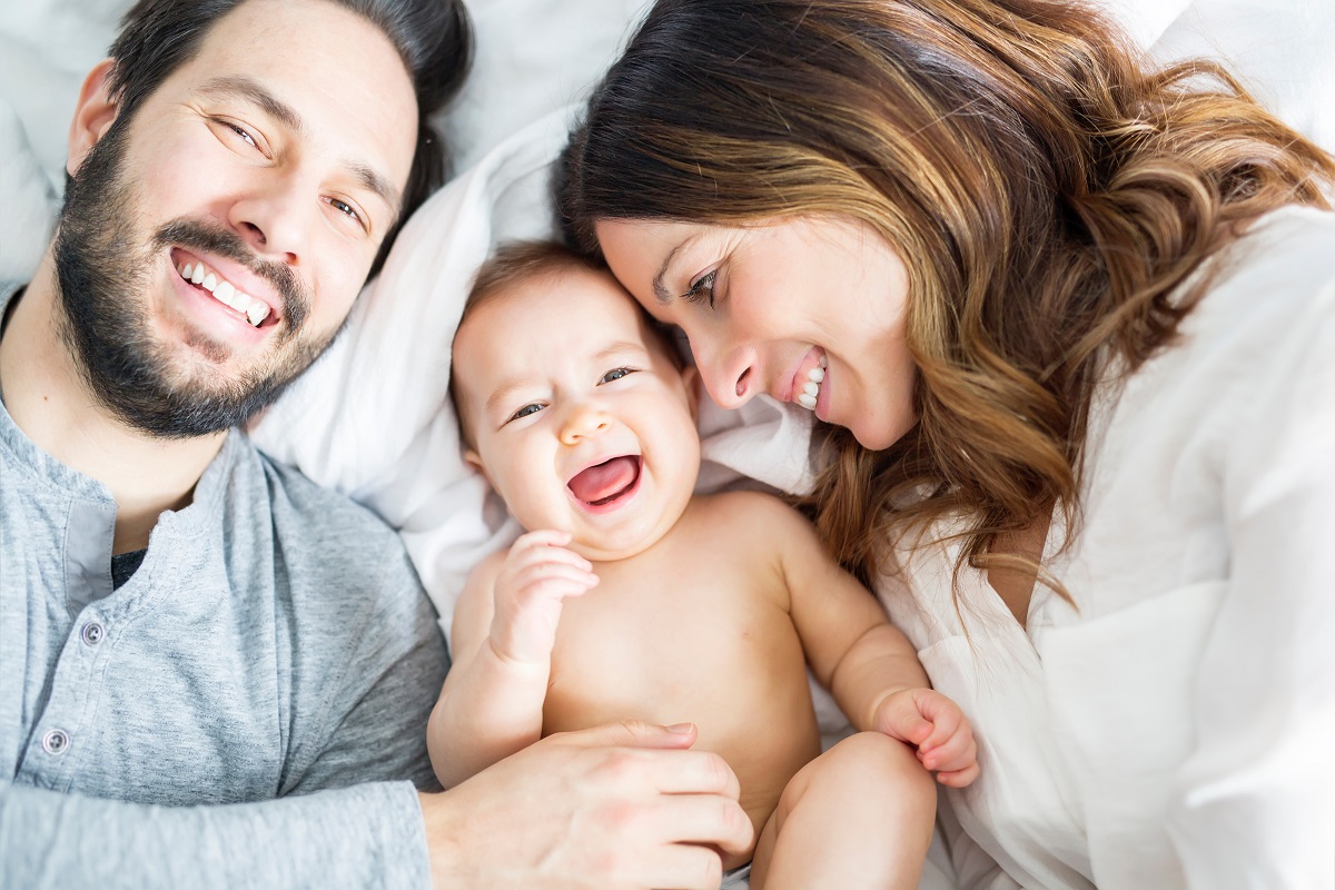 Junge glückliche Familie die mit ihrem Kind auf dem Bett liegen