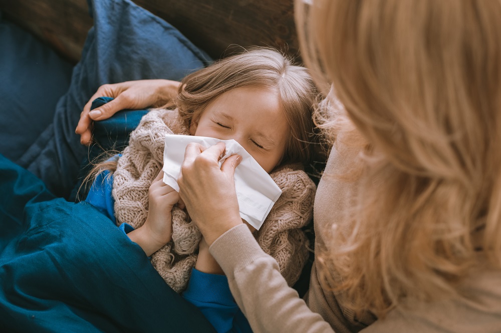 Mutter pflegt krankes Kind mit Schnupfen