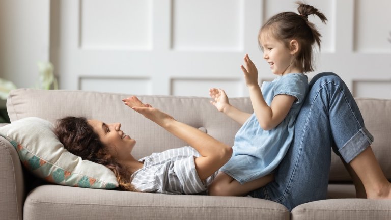 Lächelnde Mutter spielt mit ihrer kleinen Tochter