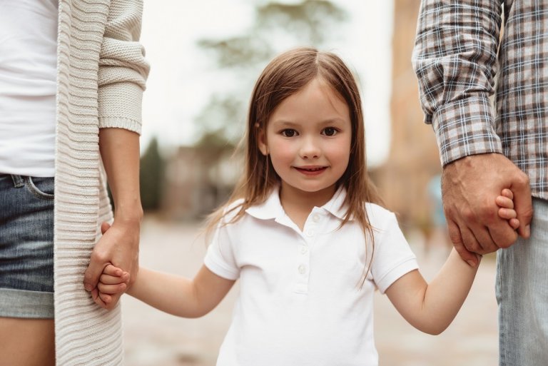 Mädchen Hand in Hand mit Eltern