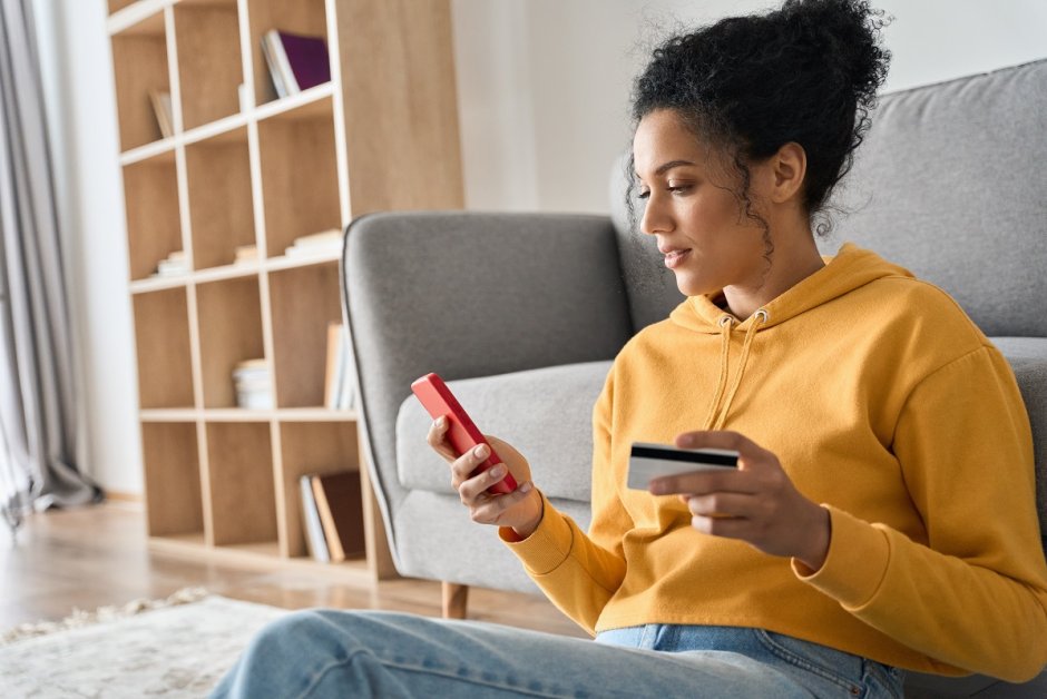 Frau auf Sofa mit Smartphone und Kreditkarte