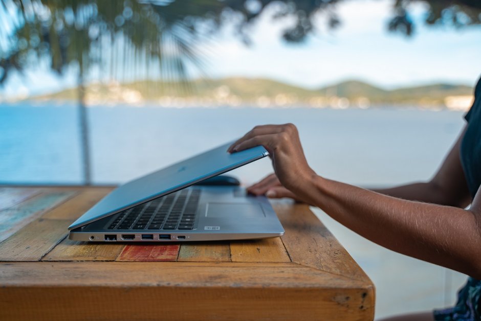 Eine Frau, die ihren Laptop am Meer aufklappt